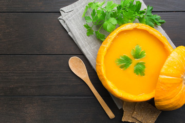 Pumpkin and carrot soup on wooden background with spoon, flat lay
