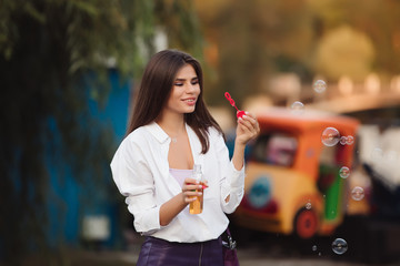 Happy girl blowing bubbles in the park