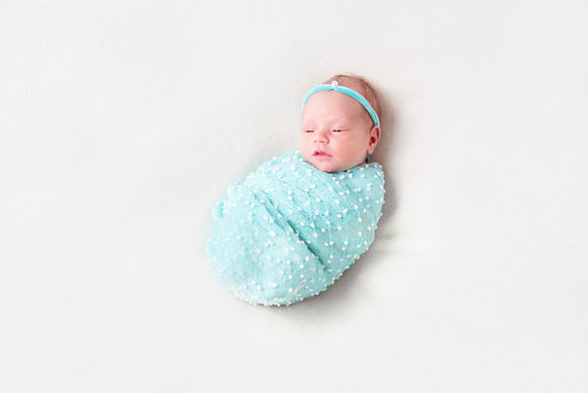Newborn Baby Wrapped In Blue Blanket On White Background