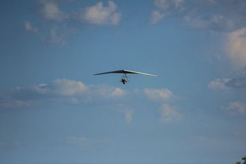 Silhouette of hang glider against blue sky with thunderclouds. Copy space.