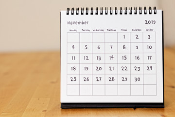 Month page: November in 2019 paper calendar with funny font on the wooden table