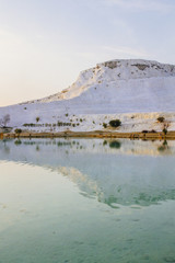 White travertine limestone mountain and its reflection in the lake in Pamukkale, Turkey