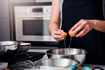 Woman girl baker in kitchen cooking whisk egg