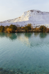 Obraz premium White travertine limestone mountain and its reflection in the lake in Pamukkale, Turkey