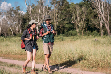 Happy young couple walking hiking in forest for camping tent together