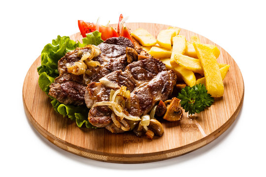 Grilled steak with french fries and vegetables on white background