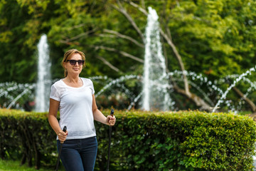 Nordic walking - middle-aged woman working out in city park