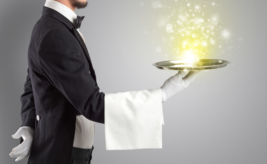 Elegant young waiter serving mysterious light on tray
