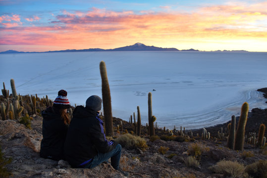 A couple enjoy sunrise views of the Salar de Uyuni from Isla Incahuasi. Uyuni, Bolivia