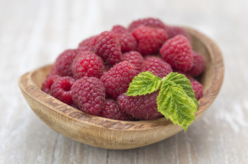 raspberry in a wooden plate on a kitchen table. 