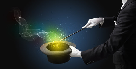 Illusionist hand starts to conjure with white glove and magic wand