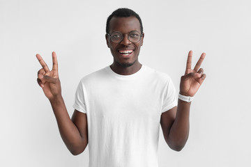Young african american man isolated on gray background in white t-shirt with optimistic smile,...