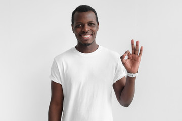 Fototapeta premium Young black man having happy look, smiling, gesturing, showing OK sign. African male showing OK-gesture with his fingers. Body language concept