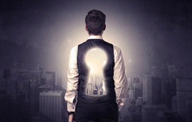 Fototapeta na wymiar Young businessman standing and thinking with keyhole on his back and city graphic around