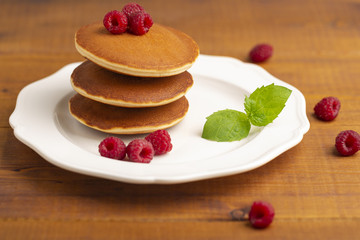  Small pancakes with raspberry and mint on wooden background