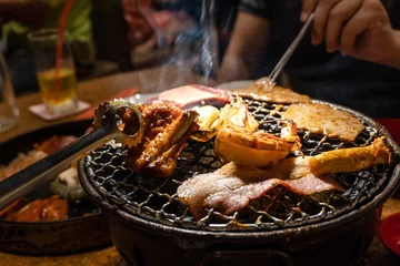 Fototapeten Group of people eating korean barbecue yakiniku inrestaurant © Kittiphan