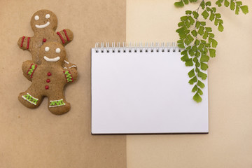 Ginger bread cookies on craft background. Blank notepad with leaf of fern. Christmas mockup. Top view.