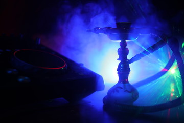 Shisha party club concept. Dj mixer with on dark nightclub background with stylish oriental shisha.