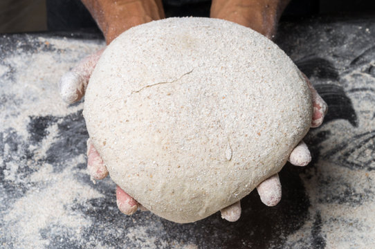 Male hands kneading dough on sprinkled