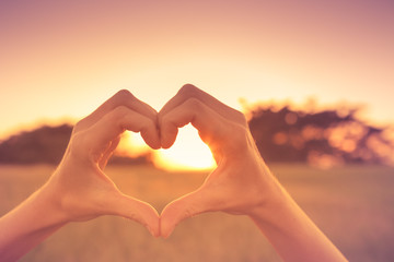 Fototapeta na wymiar Hand shaped heart against beautiful sunset.