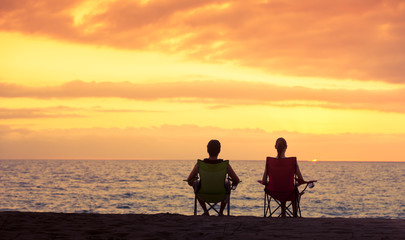 Fototapeta na wymiar Couple siting on the beach watching the sunset. 