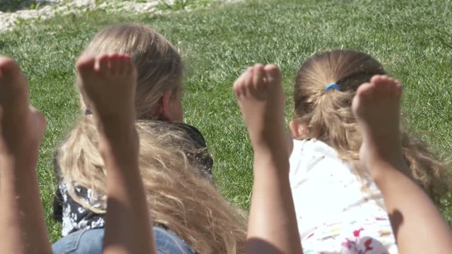 Little girls barefoot lying on the lawn on a warm summer day.