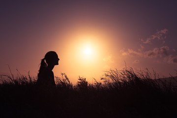 Young woman sitting out doors relaxing watching the beautiful sunset. People feeling at peace in nature. 