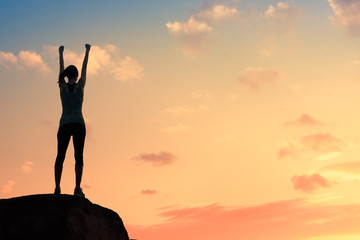 Strong motivate woman standing on rock with fist in the air. - obrazy, fototapety, plakaty