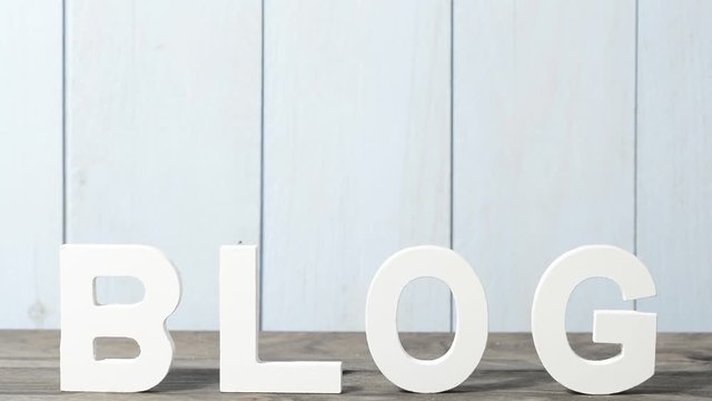 BLOG escrito en letras de madera blanca sobre la mesa de madera gris y pared azul