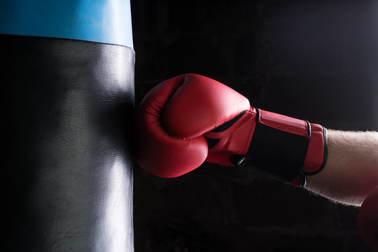 Tough Man Hitting Punching Bag With Boxing Glove.