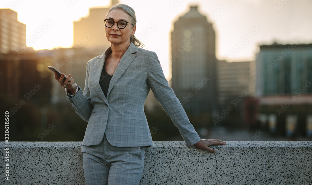 Wall mural senior businesswoman outdoors with mobile phone