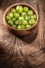 Gooseberries in round bowl on vintage wooden background