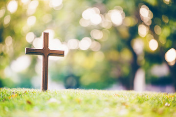 The cross standing on meadow sunset and bokeh background.Cross on a hill as the morning sun comes up for the day.The cross symbol for Jesus christ.Christianity, religious, faith, Jesus or belief.