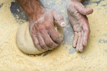 Male hands kneading dough on sprinkled