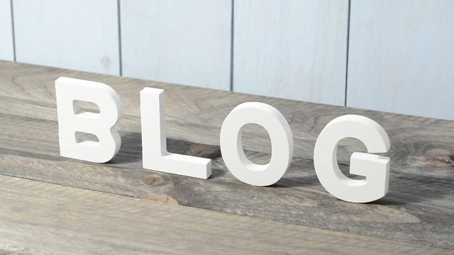 BLOG escrito en letras de madera blanca sobre la mesa de madera gris y pared azul