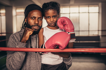Coach with a boxer kid standing near a boxing ring