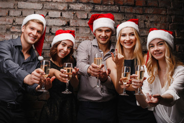 New Year, event, party, holiday, fun. Company of cheerful friends in Santa caps invite to join to Christmas celebration