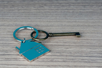 key and house shape key tag on wooden table. home security and buying house concept