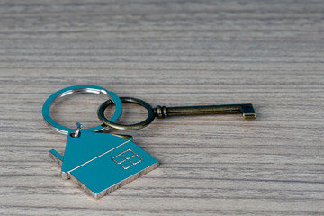 key and house shape key tag on wooden table. home security and buying house concept