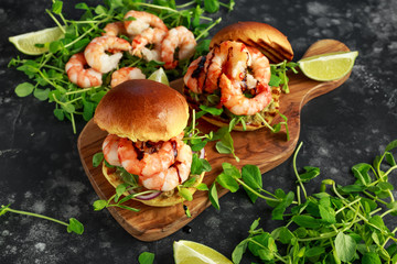 Healthy Tasty prawn grilled burger with pea shoots and sweet chilli dip served on wooden board with...
