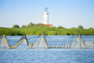 Reti da pesca con un faro sullo sfondo