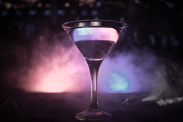 glass with martini with olive inside. Close up view of glass with club drink on dark foggy toned background. Club drink concept