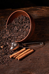 Dry tea leaves in clay bowl on black background. selective focus