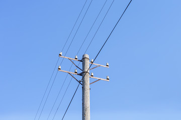 Old telephone pole with wires against a clear sky