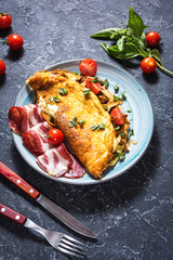 Omelet with tomatoes, mushrooms and bacon. Breakfast on stone background.