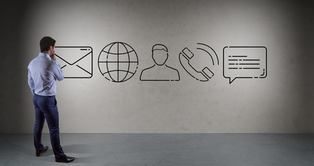 Businessman watching contact icon on a wall