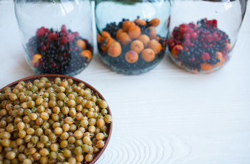 Juicy ripe berries of a gooseberry in a small basket on a wooden black surface. Gooseberry harvest