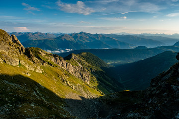 Fototapeta na wymiar Die ersten Sonnenstrahlen erleuchten eine grüne Wiese in Österreichs Bergen