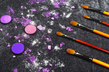 professional brushes and purple crashed eye shadows lying on a black background. concept of healthy...