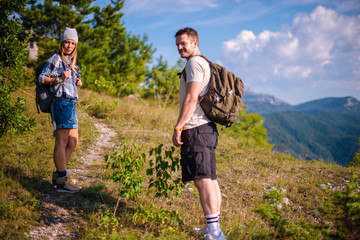 Marveling the view on the top of the mountain. Young couple at the summit enjoying the view.